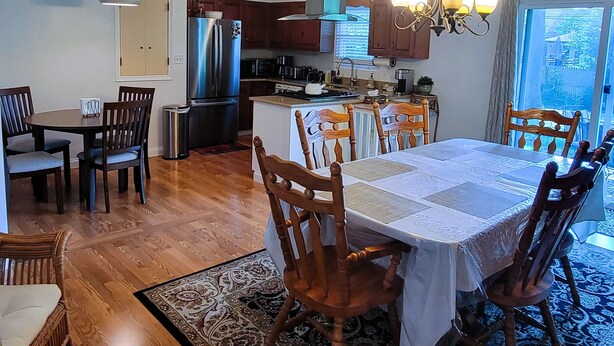 A spacious dining area with a large table and chairs, a kitchen with modern appliances, and a view through a window. - Updated clean 5br house, 2(1/2) bath close to Notre Dame. (South Bend)