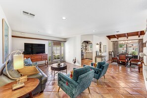 Relax in a spacious living area with a large flat-screen TV, comfortable seating, and a dining table.