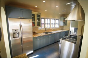 Una cocina moderna con electrodomésticos de acero inoxidable, armarios grises y un ventanal que proporciona luz natural.