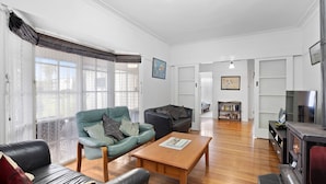 A living room with a green armchair, a black sofa, a wooden coffee table, and a fireplace. - Glyndon Family Getaway the perfect family retreat. (VENTNOR)
