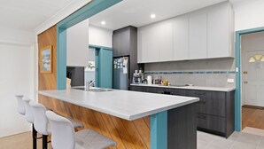 A modern kitchen with a central island, grey cabinets, and teal accents. - Glyndon Family Getaway the perfect family retreat. (VENTNOR)