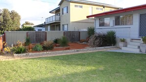 Ein Wohnhaus mit eingezäuntem Garten, einem Haus mit rotem Dach und einem zweistöckigen Gebäude im Hintergrund.