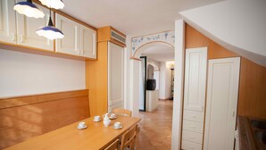 Una cocina con armarios de madera, una mesa de comedor con sillas y piso de baldosas.