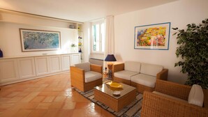 Una sala de estar con muebles de mimbre, una mesa de centro y un ventanal con cortinas.