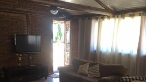 A living room with a brown sofa, a television, and a patterned rug. - Chácara Vovó Joana (Atibaia)