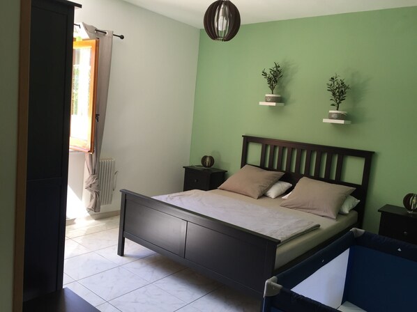 A bedroom with a bed, bedside tables, a radiator, and a window with curtains.