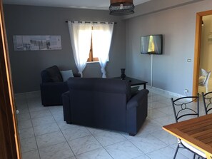 A living room with a sofa, a TV, and a table.