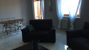 Una sala de estar con sofá, una mesa de comedor con sillas y una mesa de centro.