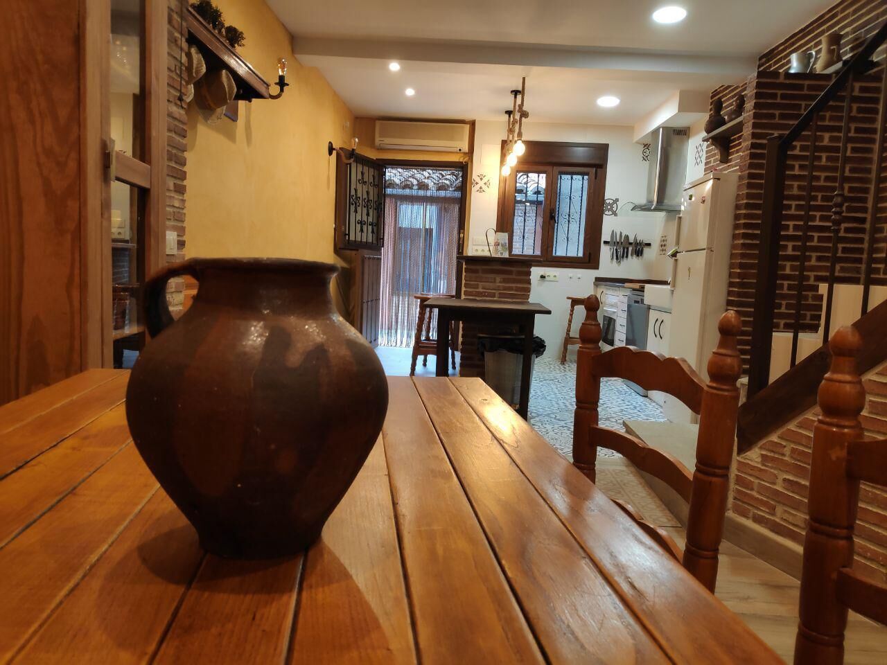 Una mesa de madera con un jarrón de cerámica grande al frente.