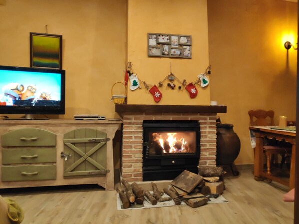 Un salon chaleureux avec une cheminée, un téléviseur et des décorations de Noël.