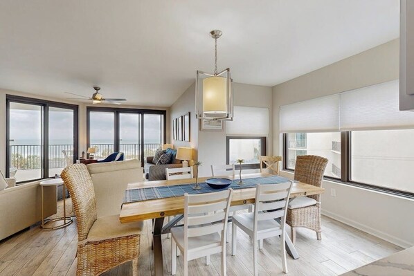 A spacious living area with a dining table, chairs, and a ceiling fan.