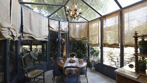 A conservatory with a round table, chairs, and a chandelier. - Welcome to La Maison du Bonheur (Gordes)