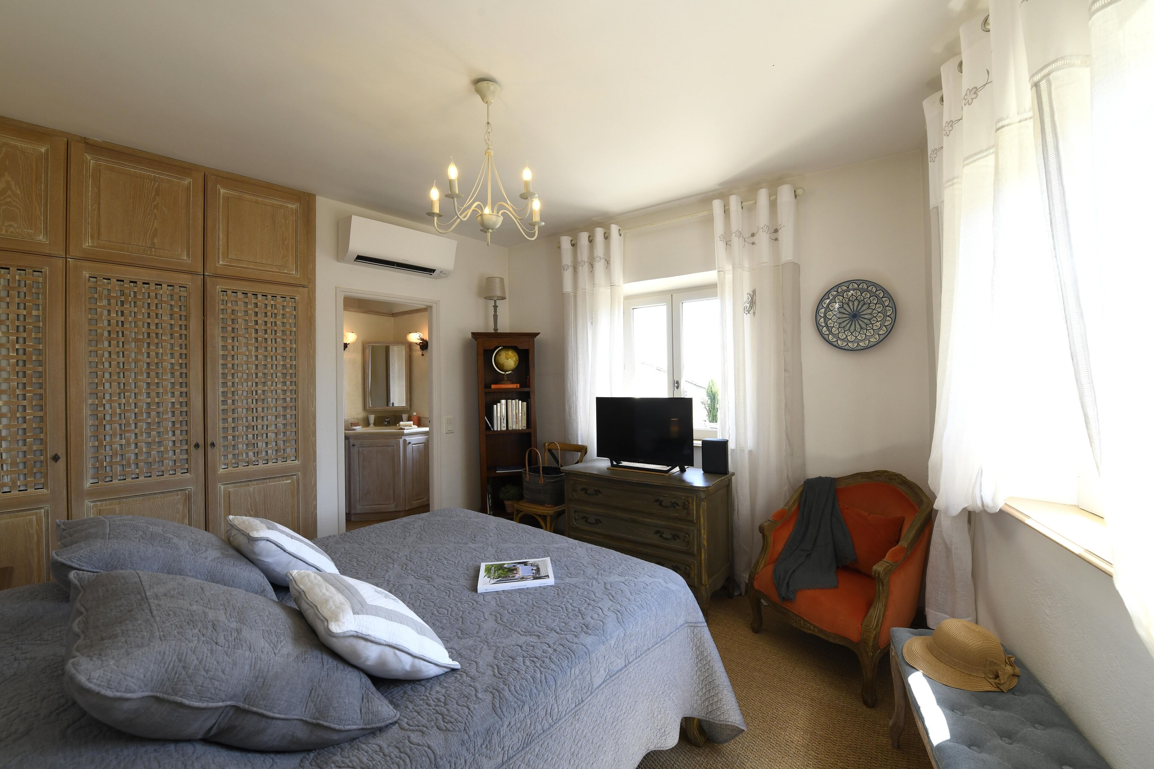 Una camera da letto con un letto, una televisione, una sedia e un comò.