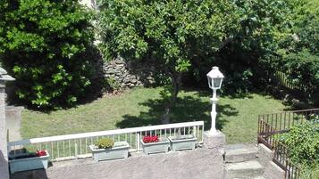 Un mur de pierre avec un petit espace aménagé en jardin, un lampadaire blanc et une rambarde en métal.