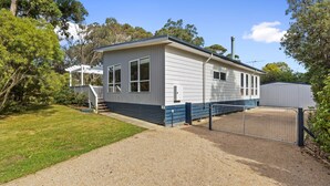 A single-story mobile home with a covered porch, a fenced yard, and a gravel driveway. - Cowes Beach and Boat House (COWES)