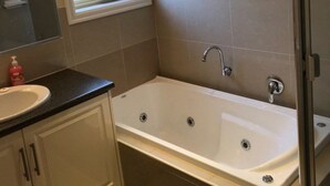 A bathroom with a white bathtub, a sink, and a mirror. - Jewel on Jenner in Cowes (COWES)