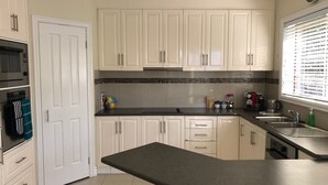 A kitchen with white cabinets, a black countertop, and a window with blinds. - Jewel on Jenner in Cowes (COWES)
