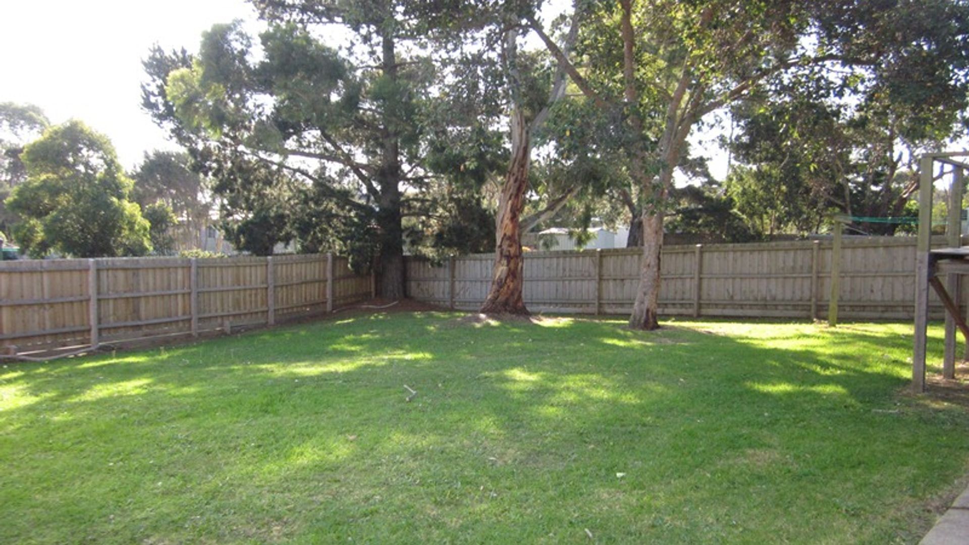 Ein Garten mit Holzzaun, Baum und Rasenfläche.