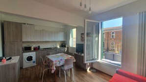 A compact kitchen with modern appliances, a dining area with a table and chairs, and a large window offering a view of a building. - BEST VIEW AND SUNNY Cà DEL SOL IT027042C2W4RXWZRV (Venezia)