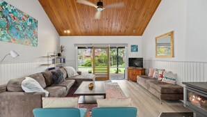 Amplia sala de estar con techo de madera, chimenea y un ventanal con vistas al exterior.
