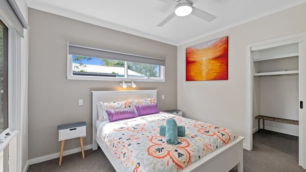 A bedroom with a bed, bedside tables, a window, a ceiling fan, and a painting. - Sanders Beach House in Silverleaves (SILVERLEAVES)