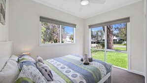 Un dormitorio con cama, dos ventanas y vistas al exterior.