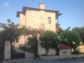 A stone building with a tiled roof, a small window, and a gate.