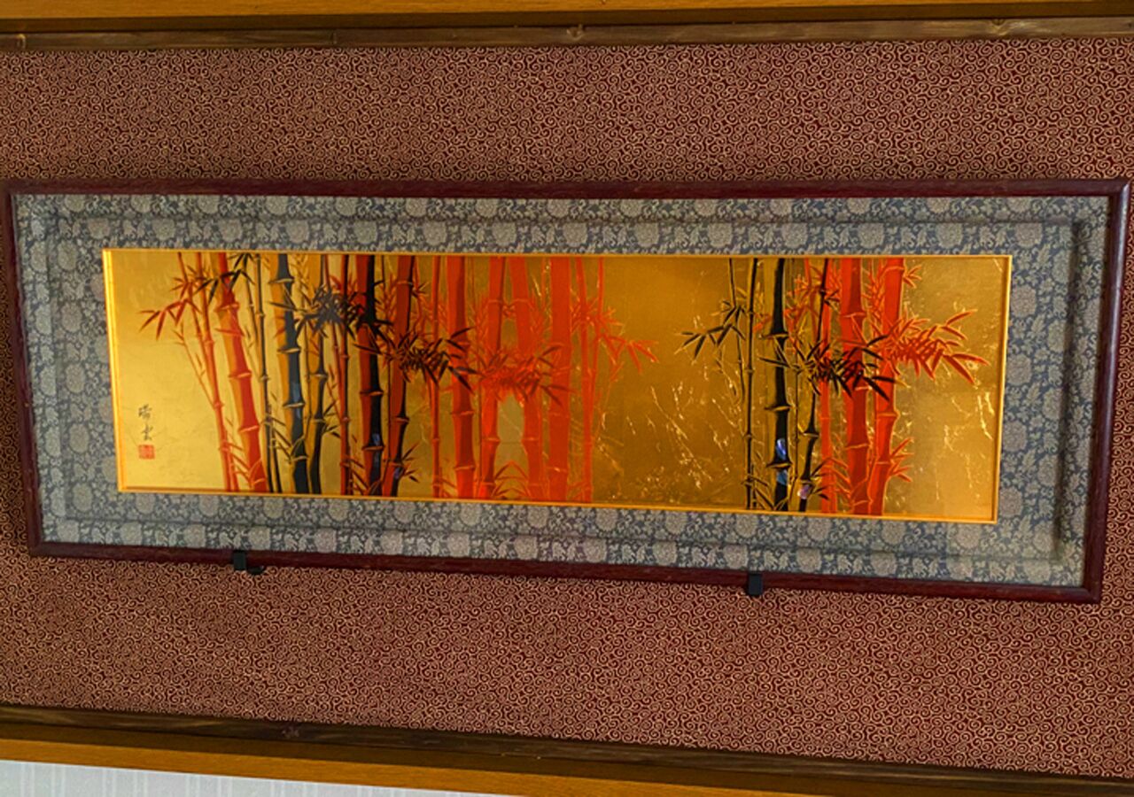 A framed artwork of bamboo on a textured wall.