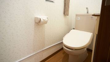 A small bathroom with a toilet, a toilet paper holder, and a towel hanging on a rack.