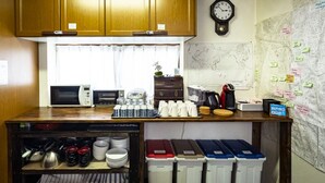 A kitchen with wooden cabinets, a microwave, a coffee maker, and various kitchen utensils. There is a clock on the wall and a map with notes.