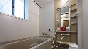 A modern bathroom with a bathtub, a toilet, and a shower.