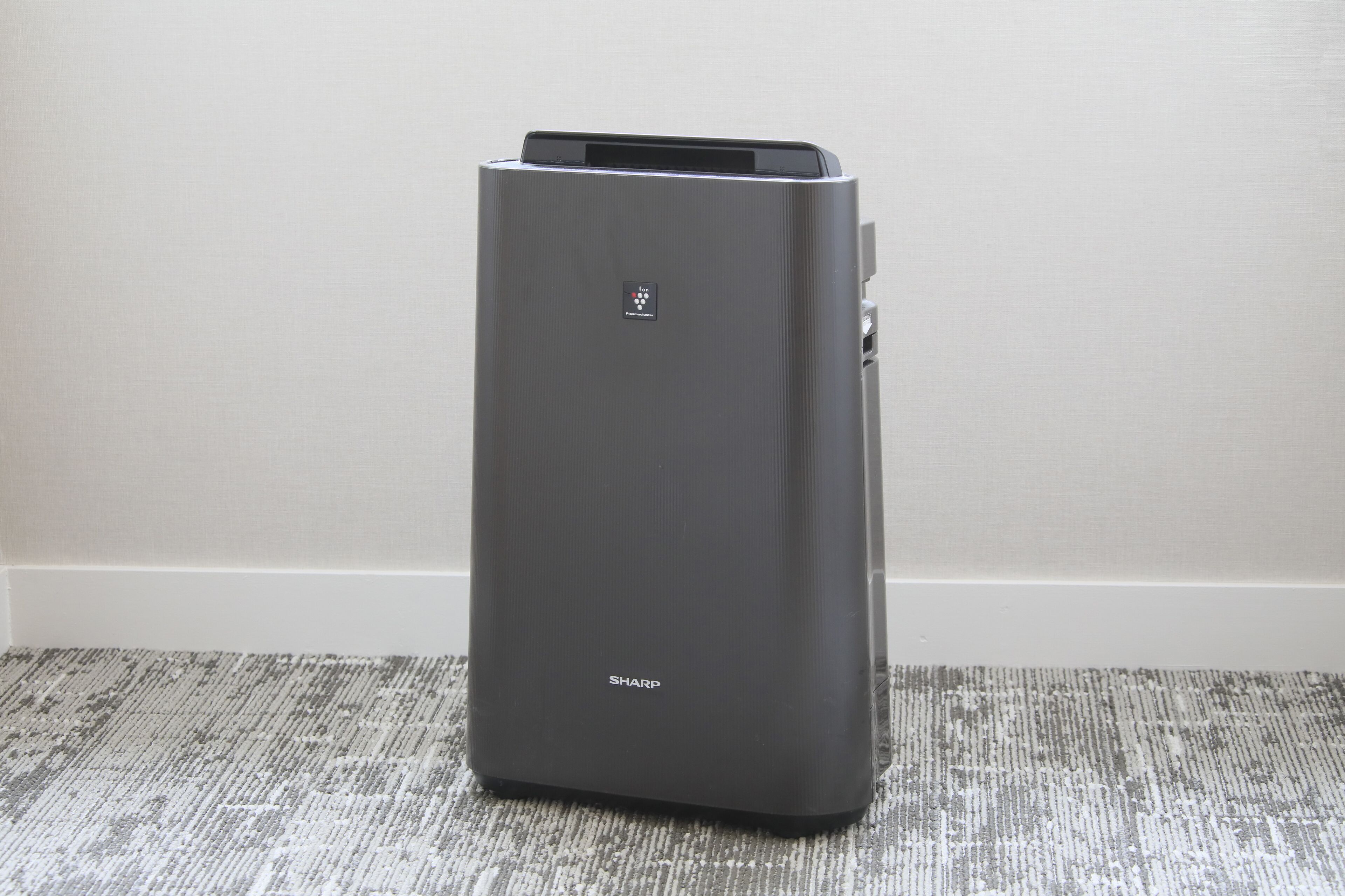 A gray, modern, stationary device with a control panel and a brand name 'SHARP' on the front.
