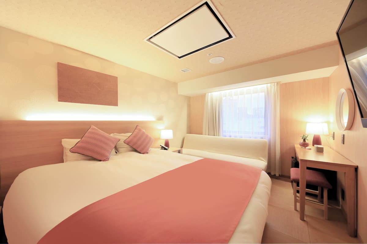 A hotel room with a large bed, a desk, and a chair.