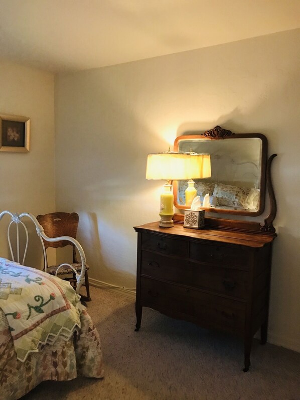 A bedroom with a bed, a dresser with a mirror, a chair, and a lamp. - LAVENDER WOODS HOUSE (Farmington)