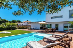 A modern house with a swimming pool, outdoor furniture, and a well-maintained lawn. - Premium Villa with Private Pool in Aldeia do Meco (Sesimbra)