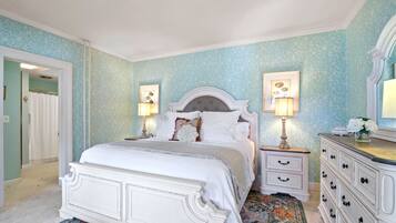 A bedroom with a large bed, two bedside tables with lamps, a dresser, and a patterned rug.