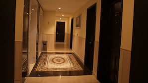 Un pasillo con suelo de mármol, un tapete estampado y puertas que dan a varias habitaciones.