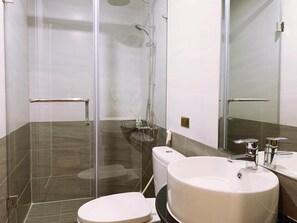 A modern bathroom with a glass-enclosed shower, a white toilet, and a large sink with a mirror above it.