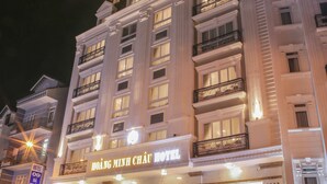 Un hotel con un letrero llamativo, varios balcones y una entrada bien iluminada.