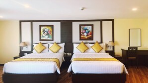Habitación de hotel con dos camas, una mesita de noche, una lámpara y dos cuadros enmarcados con motivos florales en la pared.