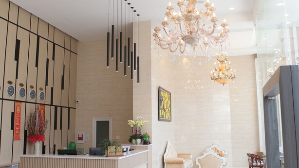 Un moderno vestíbulo de hotel con mostrador de recepción, zona de estar y candelabros decorativos.