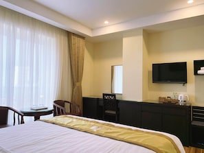 Une chambre d’hôtel équipée d’un lit, d’un bureau, d’une chaise, d’une télévision et d’un mini-bar.