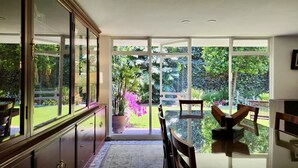 A spacious room with a large glass door leading to a lush garden. - Casa Tamayo (Mexico City)