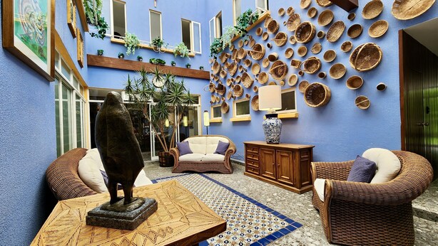 A cozy interior with wicker furniture, a decorative statue, and a wall adorned with woven baskets. - Casa Tamayo (Mexico City)