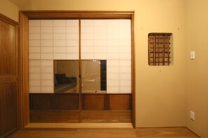 A room with a sliding door, a small window with a grid pattern, and a wooden floor. - Suiren (Kyoto)