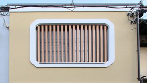 La façade d’un immeuble avec une grande fenêtre, une porte et un petit espace de porche.