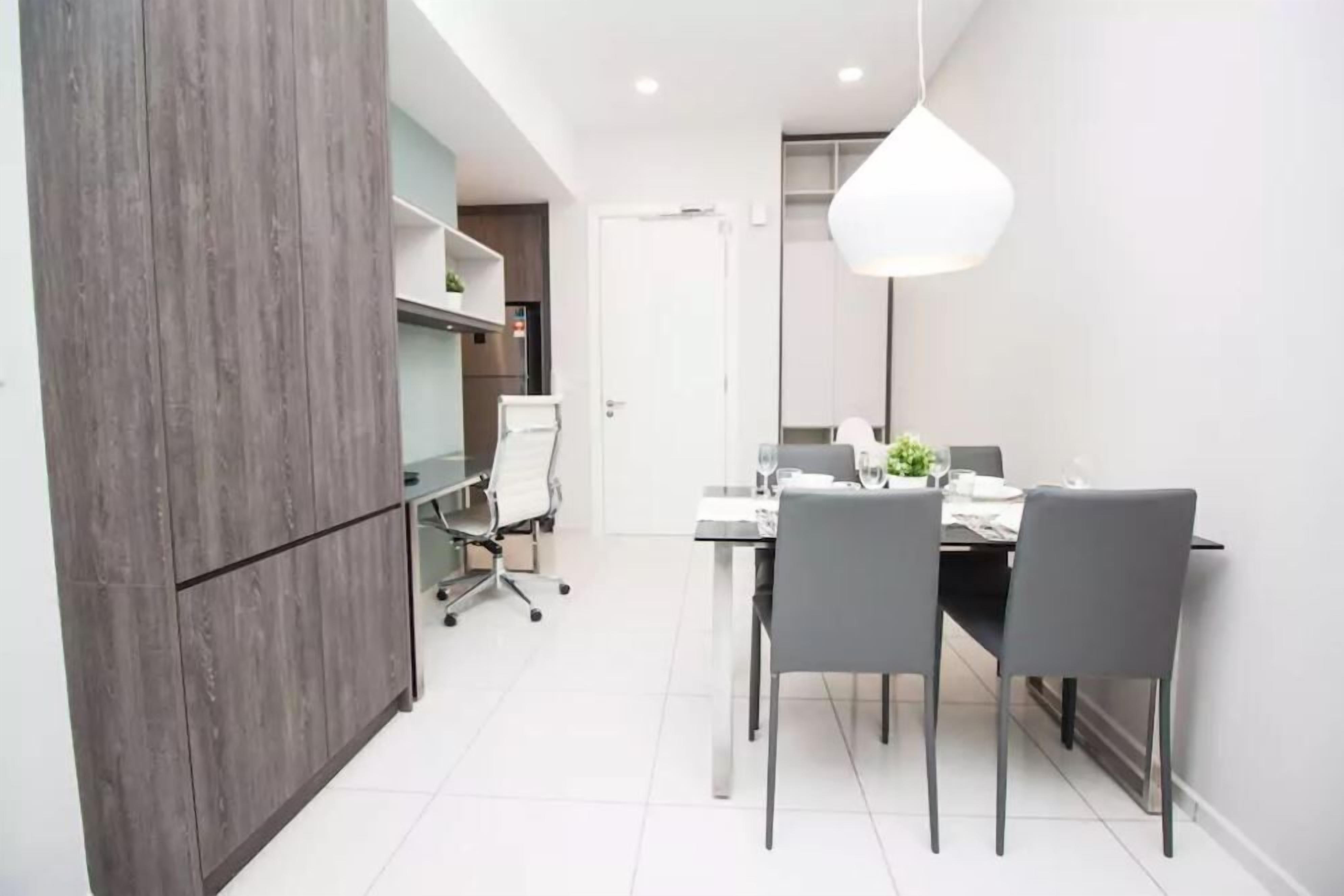 A modern dining area with a table set for four, a white door, and a pendant light.