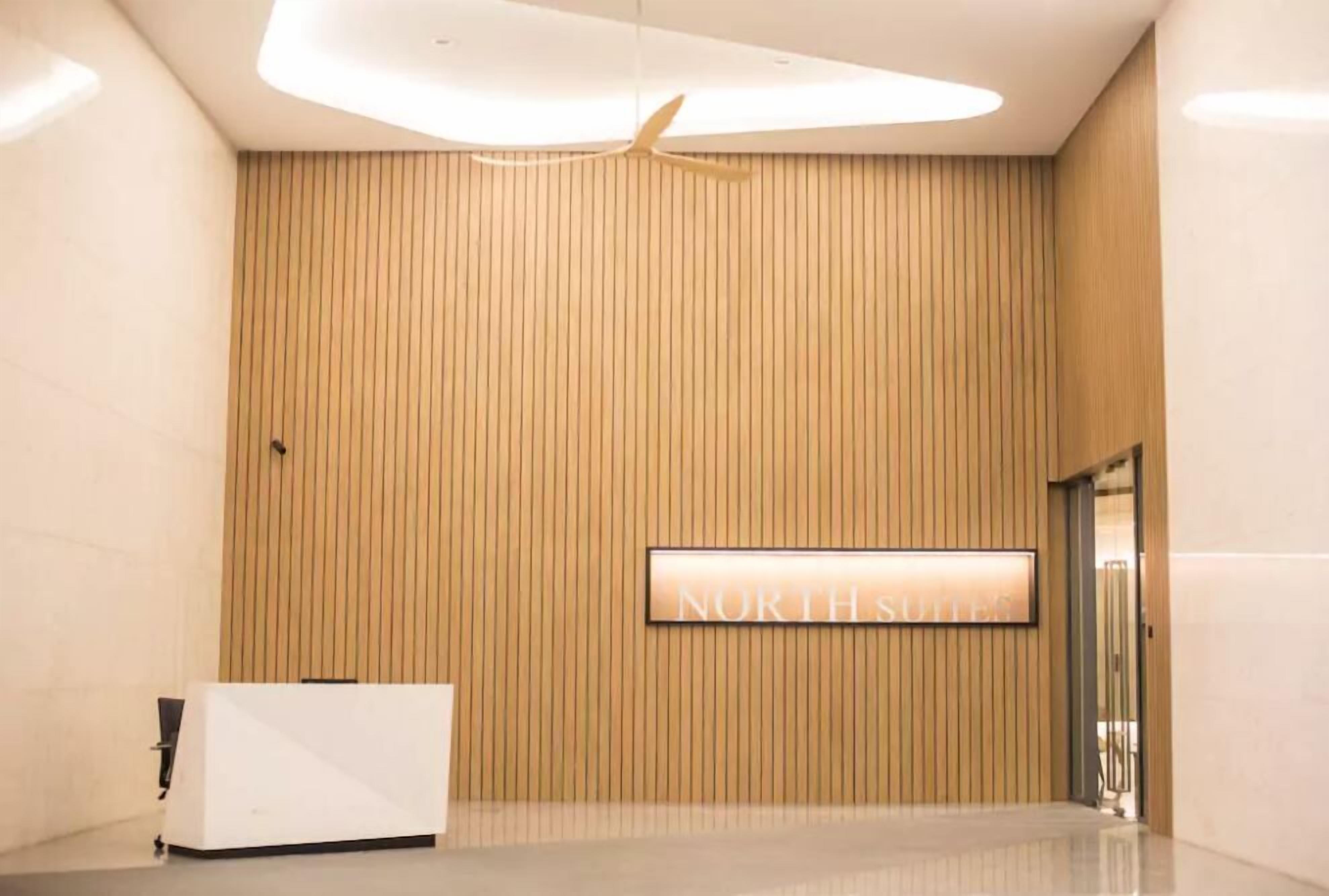 Een receptiegedeelte met een wand van houten panelen, een receptiebalie en een bordje met de tekst 'NORTH STUDIO'.