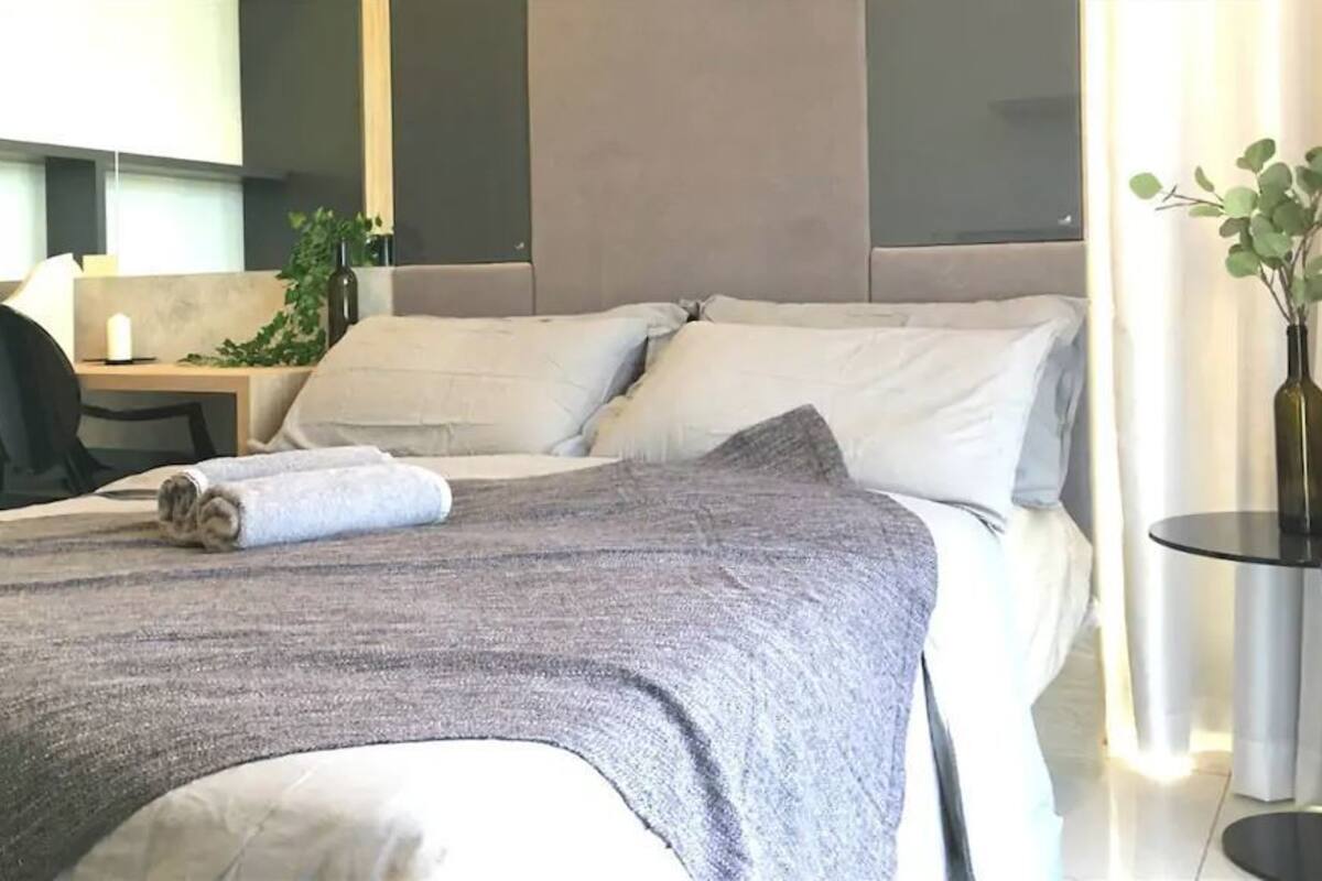 A modern hotel room with a large bed, a desk, and a chair.