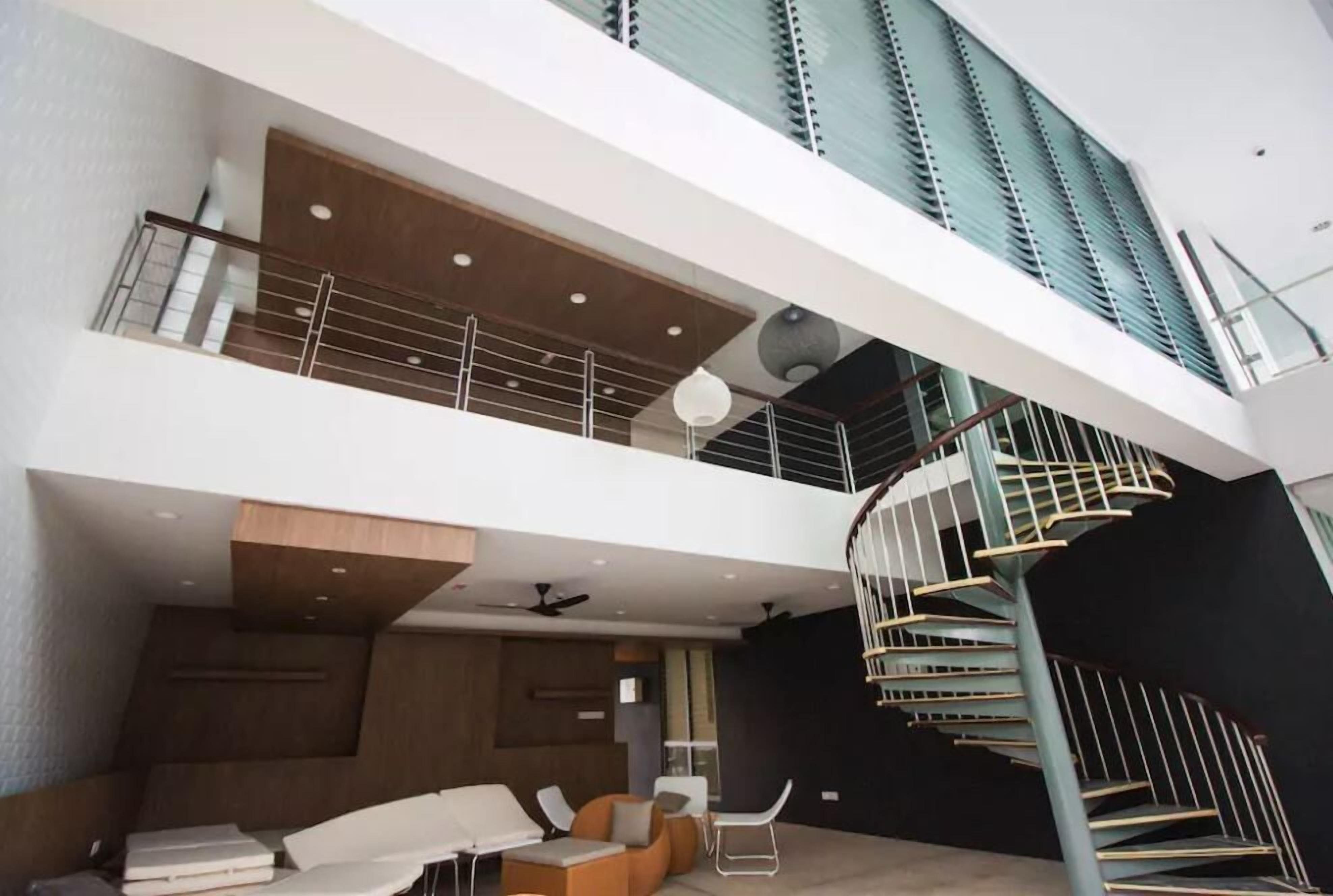 A multi-level interior with a spiral staircase, modern furniture, and a mezzanine level.